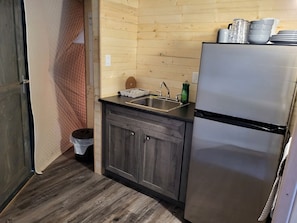 A compact kitchen with a sink, cabinets, and a refrigerator. - Family-Friendly Dome Perfect for a Cozy and Tranquil Escape in Alberta (Beaver Mines)
