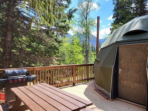 A deck with a grill, a tent, and a wooden deck railing.