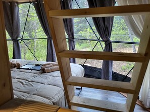 Ein Schlafzimmer mit einem Bett, einer Holzlade und einem Fenster mit Vorhängen.