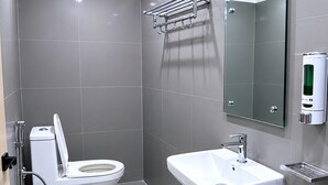 Een moderne badkamer met toilet, wastafel en handdoekrek.