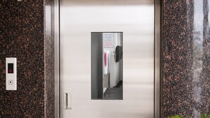Een moderne lift met een digitaal scherm, een handgreep en een bord met instructies.