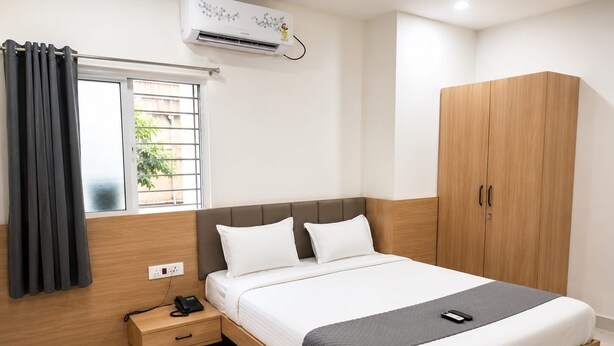 Een hotelkamer met een bed, nachtkastje, telefoon en garderobe.