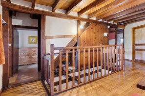 Un escalier en bois avec une rampe menant à l’étage supérieur, un cadre de porte en bois et un tapis à motifs sur le sol.