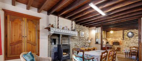 A rustic interior with a stone fireplace, wooden furniture, and a tiled floor.
