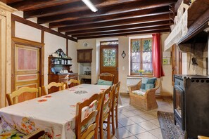 A dining area with a table set for four, wooden chairs, a fireplace, and a window with curtains.