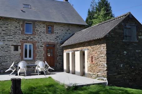 A stone building with a large window and a door, a small attached structure with a sloped roof, and two white chairs outside.. Holiday Home “La Charmille” with Private Terrace and Garden