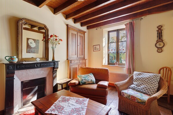 A traditional living room with a fireplace, a sofa, a wicker chair, and a mirror.