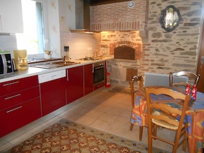 Una cocina con gabinetes rojos, una chimenea de ladrillo y una zona de comedor con una mesa y sillas.