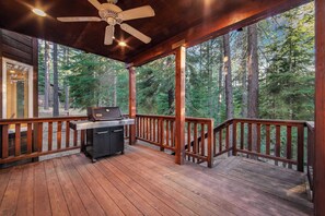 Eine überdachte Terrasse mit Grill, Holzbalkonen und Blick auf einen Wald.