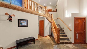 A staircase with wooden railings, a stone floor, a bench, and a door with a sign. - Alpine Osage Mountain Stay (South Lake Tahoe)