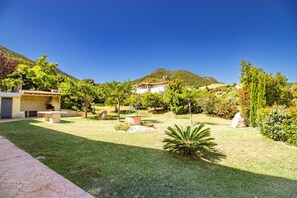Ein Wohnhaus mit Steinterrasse, kleinem Garten und Bergblick.