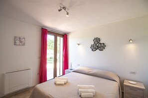 Ein Schlafzimmer mit Bett, Heizkörper, einem Fenster mit Vorhängen, einem Wandbild und einem Nachttisch.