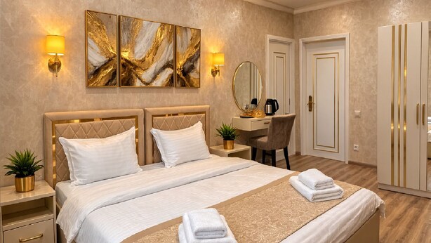 A hotel room with a large bed, bedside tables, a desk, a chair, a wardrobe, and artwork on the wall. - Sumaya Hotel (Tashkent)