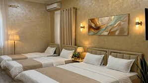 A hotel room with two beds, a large abstract painting, a potted plant, and a wall-mounted air conditioner. - Sumaya Hotel (Tashkent)