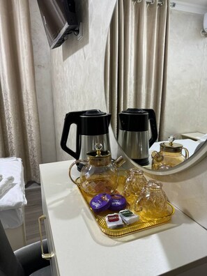 A hotel room with a white desk, a coffee maker, a bottle of honey, and a tray with honey dipper and containers. - Sumaya Hotel (Tashkent)