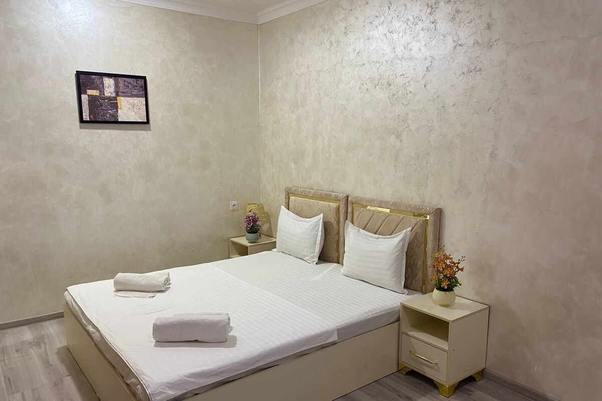 A hotel room with a bed, bedside tables, and a wall-mounted artwork.
