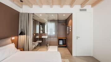 A modern bedroom with a large bed, a glass shower enclosure, and a white door.