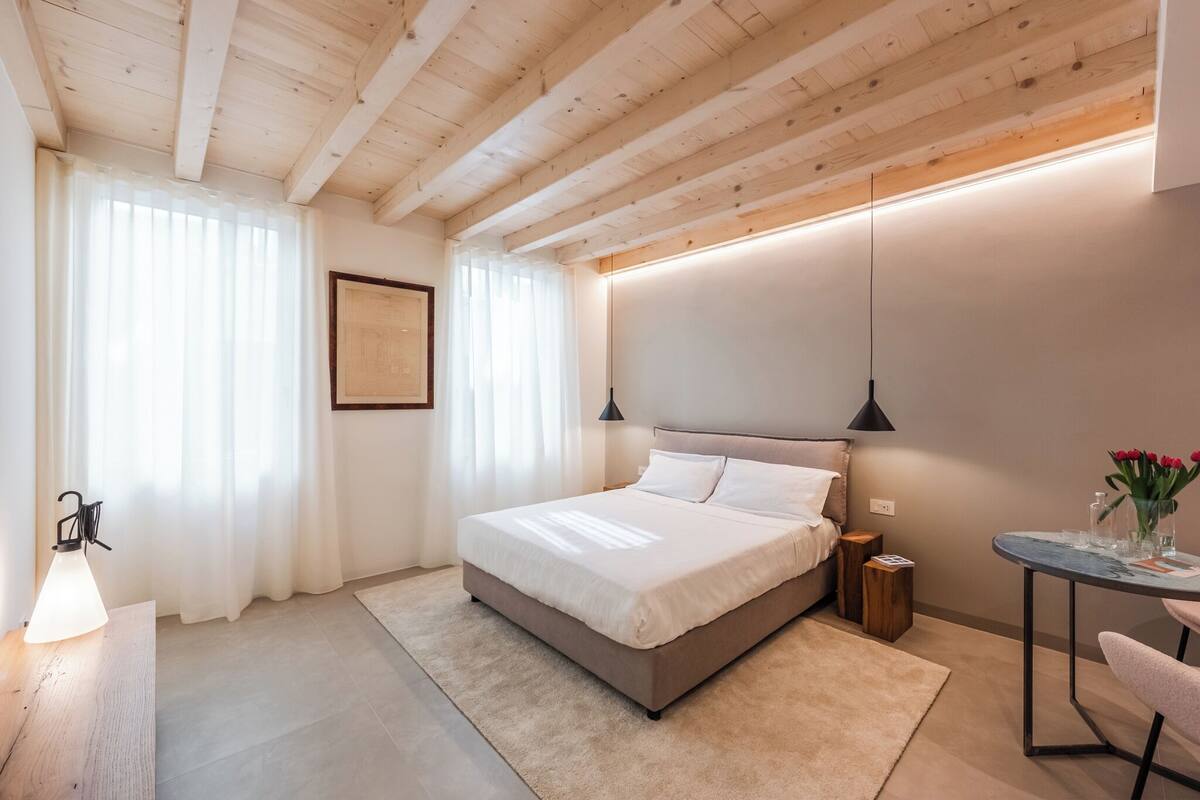A bedroom with a bed, bedside tables, a desk, and a lamp.