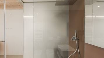 Een moderne badkamer met een glazen douchecabine, een witte wastafel en een houten plafond.