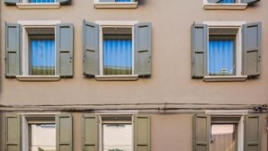 A building with multiple windows, some with shutters, and a garage door. - Margherita Home (Reggio nell'Emilia)