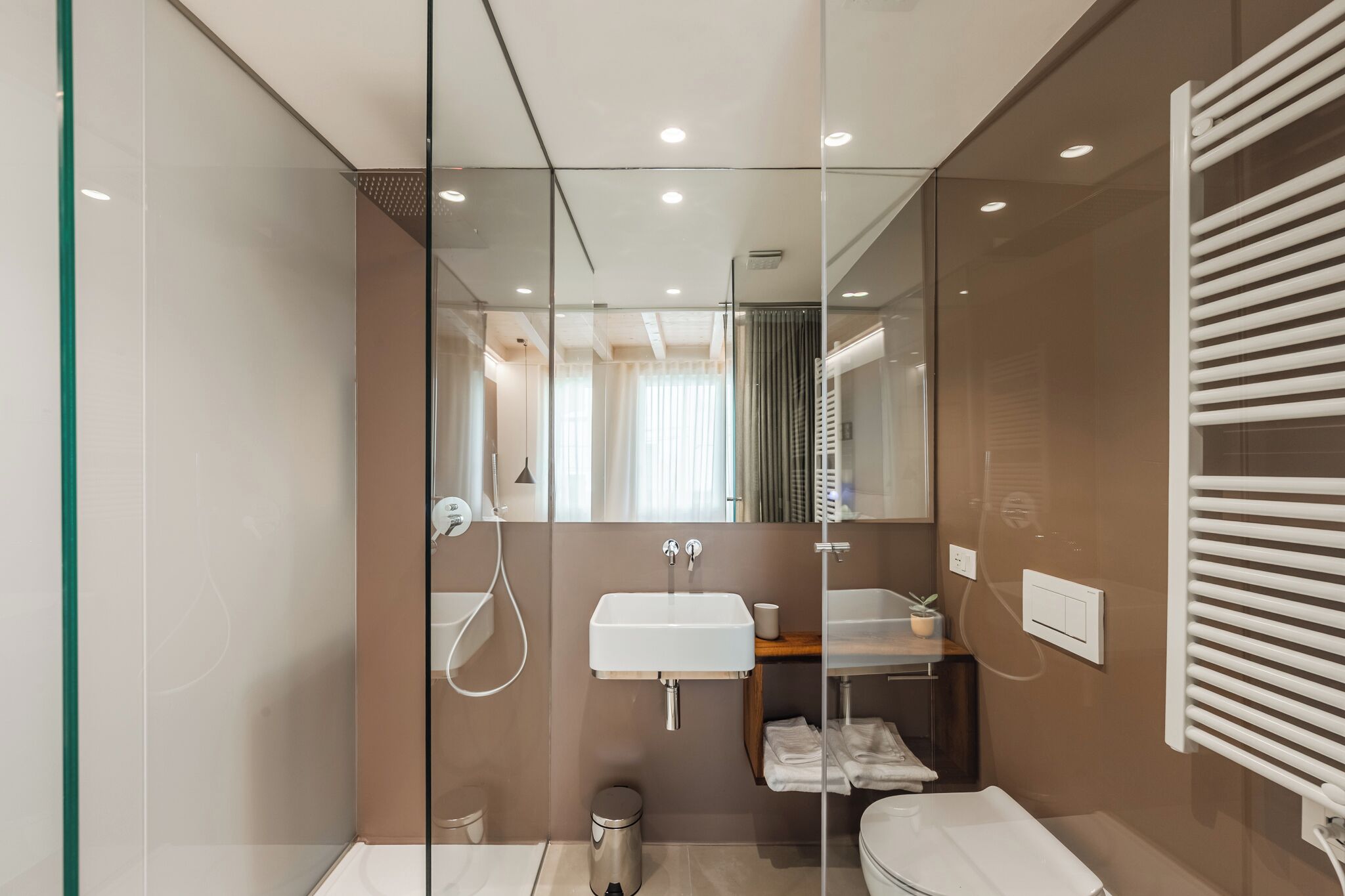A modern bathroom with a glass partition, a sink, a mirror, and a toilet.