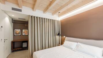 A bedroom with a large bed, a headboard, a bedside table, a lamp, and a curtain.