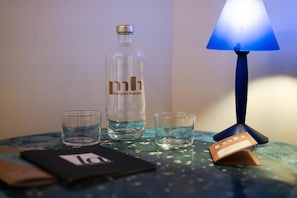 Et bord med en flaske, glas, en lampe og et kort.