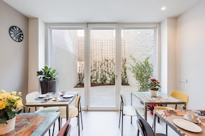 Un comedor moderno con una puerta de cristal que da a un patio, con un reloj en la pared.