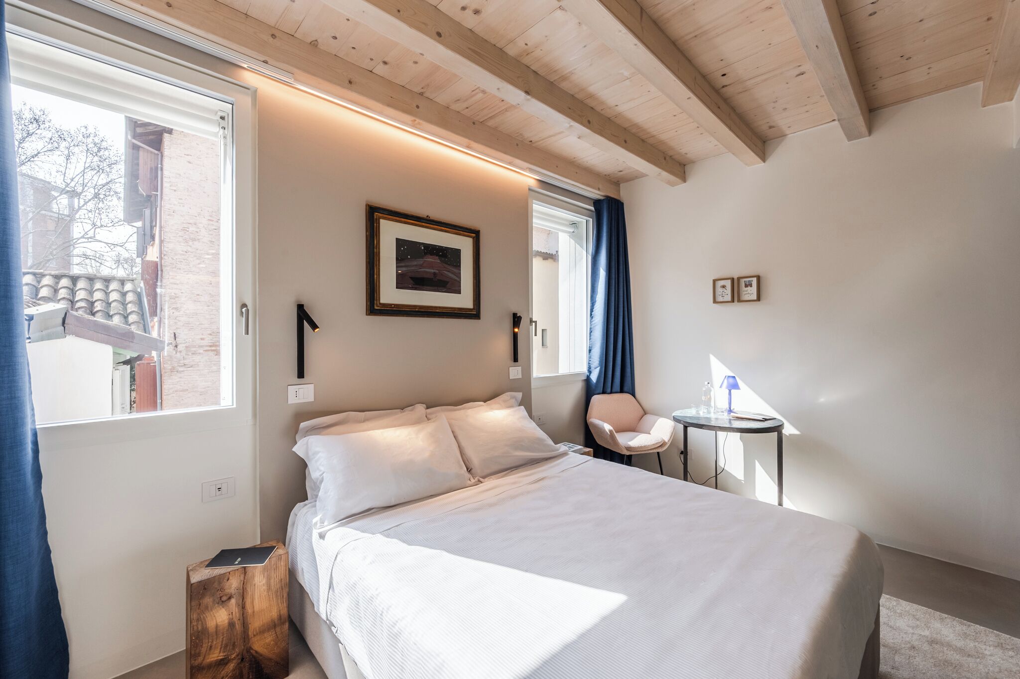 A bedroom with a bed, a small table, a chair, a window, and a door.