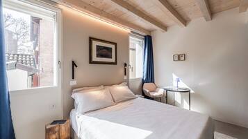 A bedroom with a bed, a small table, a chair, a window, and a door.