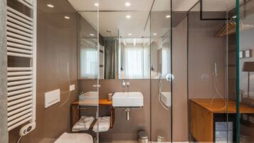 A modern bathroom with a glass shower enclosure, a white sink, and a wooden vanity.
