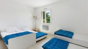 A room with two beds, a window, a wall-mounted heater, and a small shelf. - Family House with 4 Bedrooms for 13 Guests (La Plaine-sur-Mer)