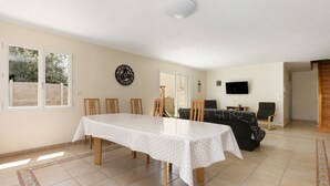 A dining area with a table and chairs, a clock on the wall, and a television in the background. - Family House with 4 Bedrooms for 13 Guests (La Plaine-sur-Mer)
