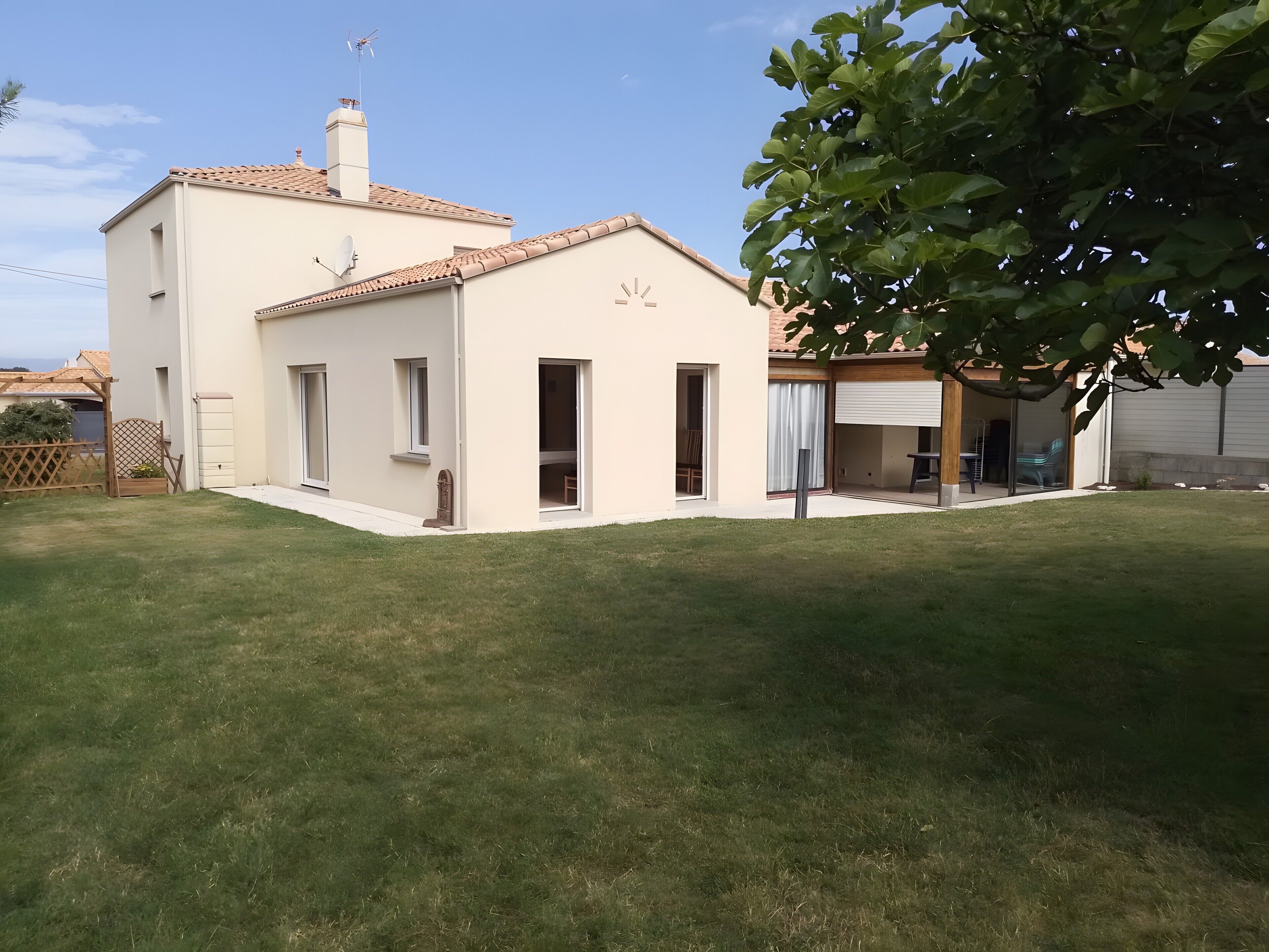 A two-story house with a tiled roof, a covered patio, and a well-maintained lawn.. Family House with 4 Bedrooms for 13 Guests