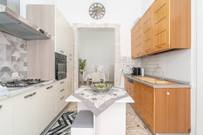 Een kleine keuken met een gasfornuis, oven, houten kastjes en een betegelde achterwand.