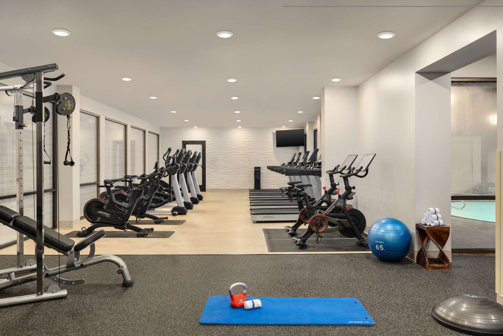 A gym with various exercise equipment, a blue mat, kettlebells, and a blue exercise ball.