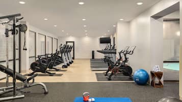 A gym with various exercise equipment, a blue mat, kettlebells, and a blue exercise ball.