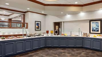 A breakfast buffet with various food items and beverages, a wooden ceiling, and framed artwork on the walls.