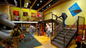 Un musée avec une pancarte indiquant la présence d’une salle où l’on peut expérimenter les effets de la gravité, une grande sculpture et un escalier.