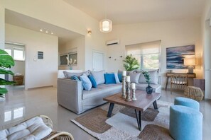 A modern living room with a sofa, coffee table, and decorative items. - Villa Marathi - Ocean View (Chania)