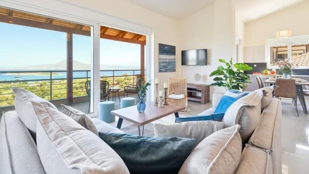 Ein modernes Wohnzimmer mit großem Fenster, Essbereich und Küche.