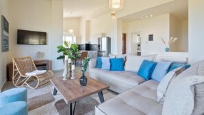 Ein modernes Wohnzimmer mit Sofa, Couchtisch, Fernseher und Essbereich.