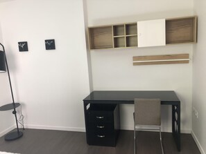 A modern room with a black desk, a chair, a floor lamp, and a wall-mounted shelf. - 111 - L'Herblinois - Wifi - Proche tram (Saint-Herblain)