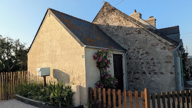 A small stone building with a sloped roof, a wooden fence, and a gravel driveway. - Family home 500 m from the beach (Saint-Marcouf)
