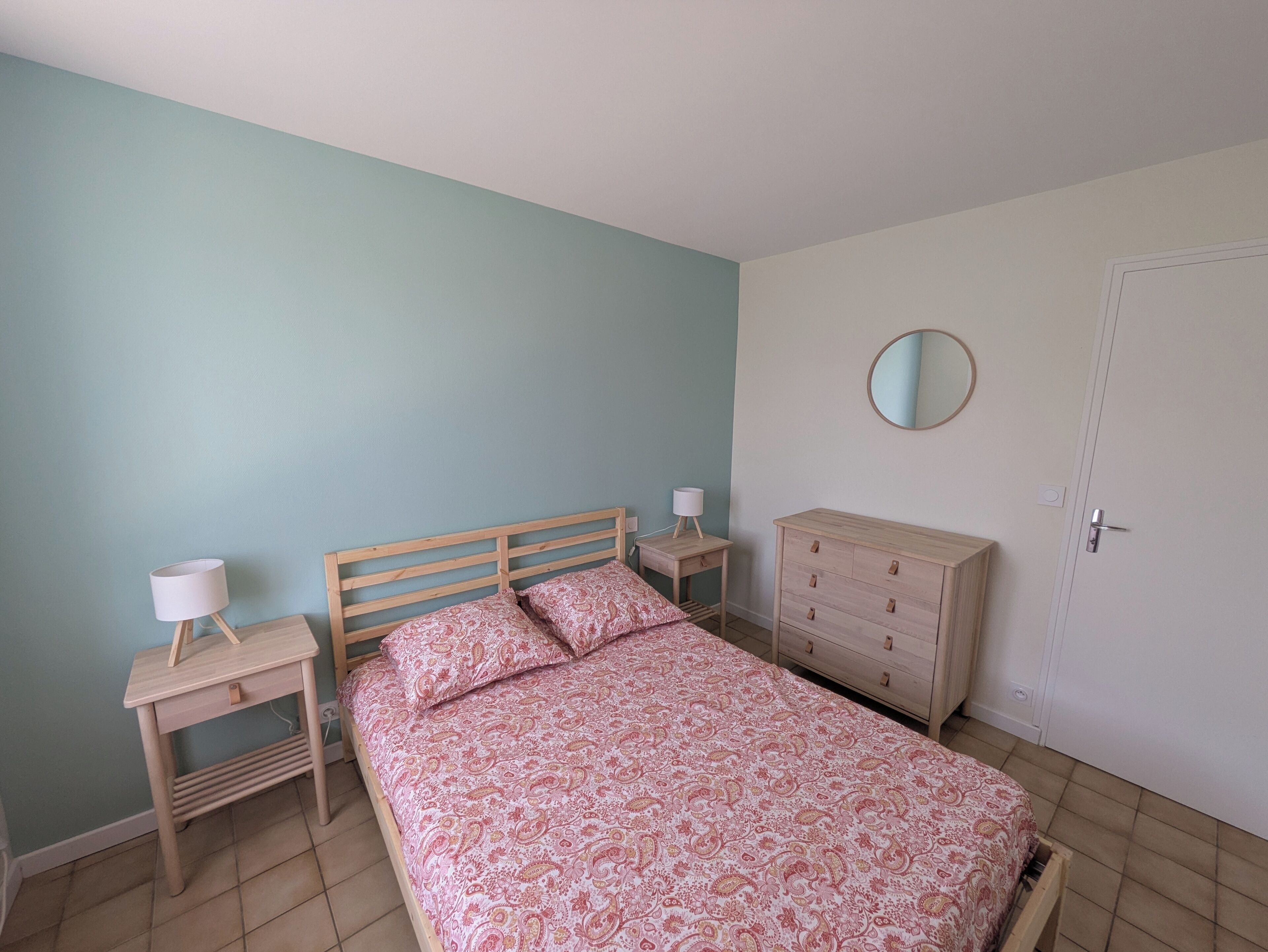 Un dormitorio con cama, mesitas de noche, cómoda y una puerta.