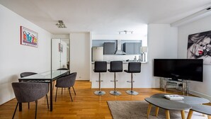 A modern living room with a dining area, a kitchen, and a TV. - Mobility Lease - Porte Dauphine - 1 large bedroom (Paris)