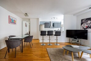Ein modernes Wohnzimmer mit Essbereich, Küche und Fernseher.