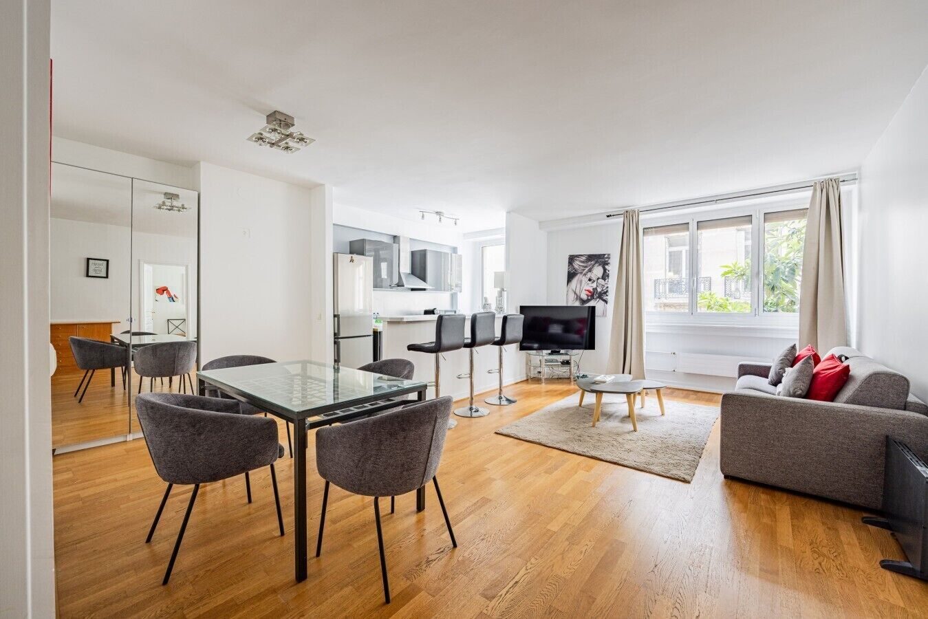 A modern living room with a dining area, a kitchen, and a TV.