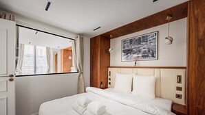 A hotel room with a large bed, a window with curtains, a wooden headboard, and a framed picture on the wall. - Luxurious 2 Bedrooms - Le Marais - Paris 3 # AC (Paris)