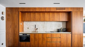 A modern kitchen with wooden cabinetry, a built-in oven, and a marble countertop. - Luxurious 2 Bedrooms - Le Marais - Paris 3 # AC (Paris)
